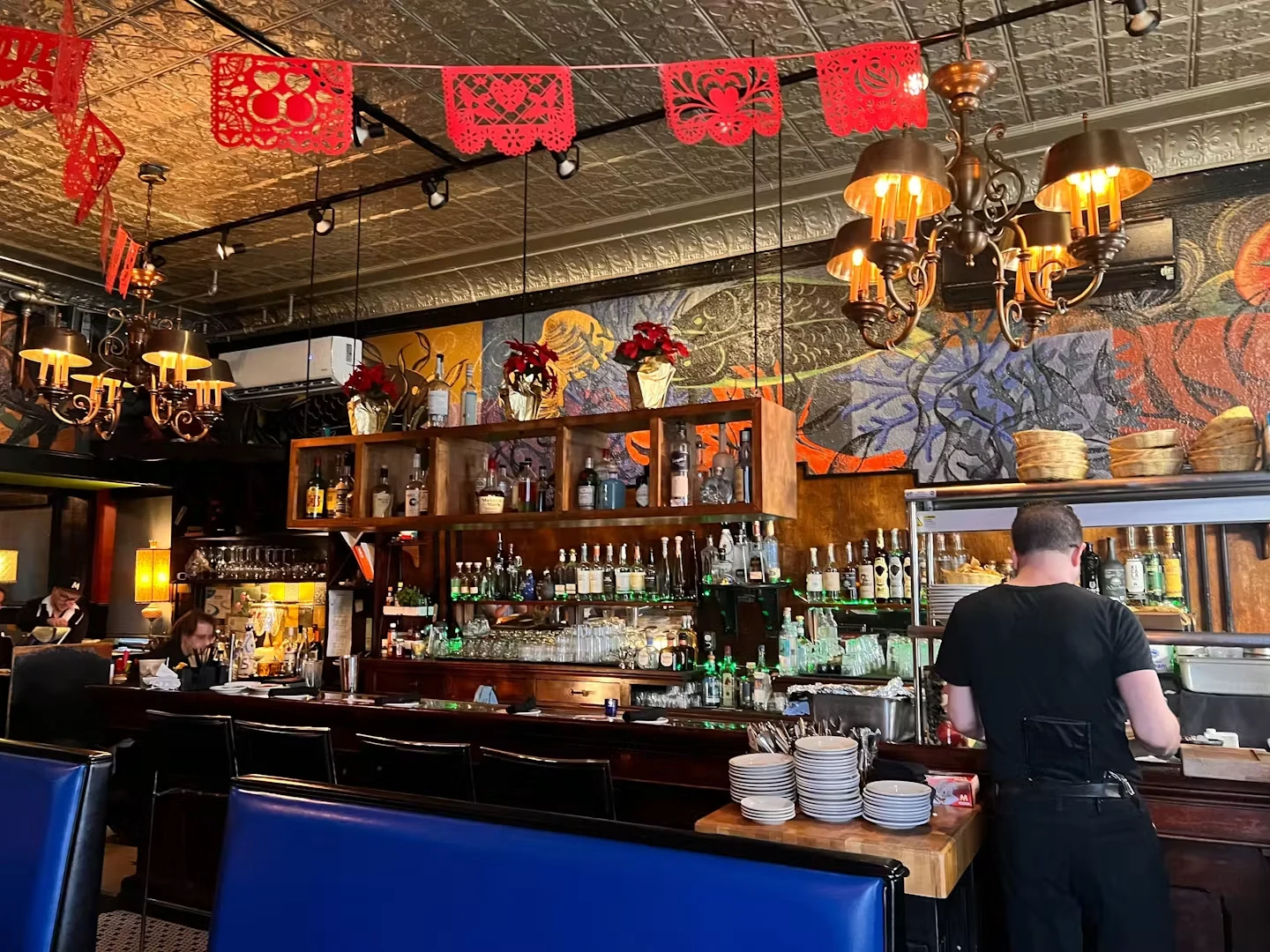La Dama’s wood bar beneath red paper banners and a patterned metal ceiling