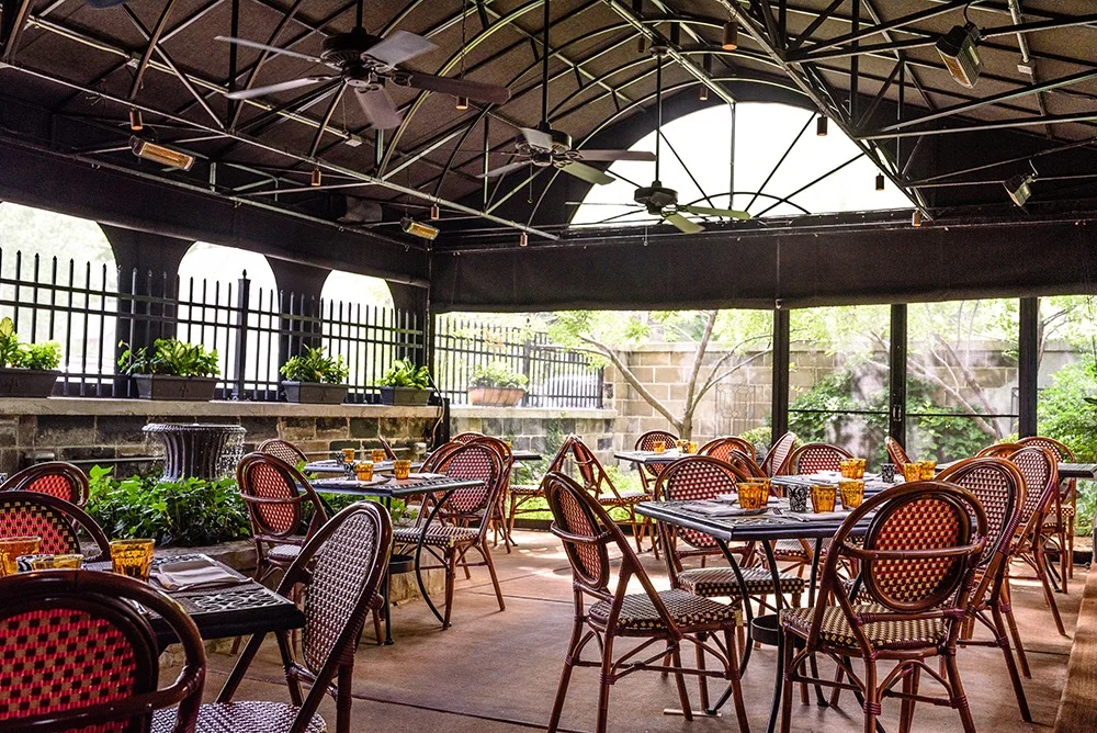 La Dama’s covered patio with dining tables, woven chairs, and ceiling fans