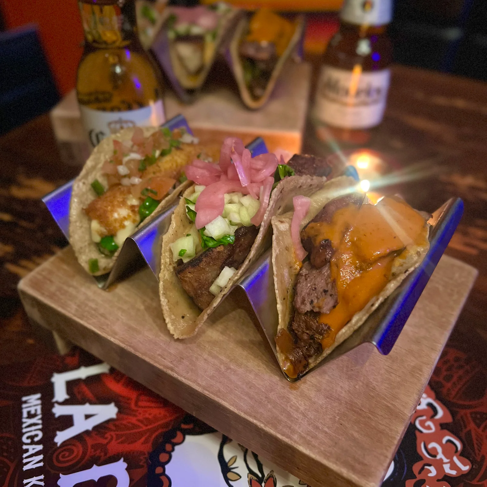 Three filled tacos on a wooden serving board.
