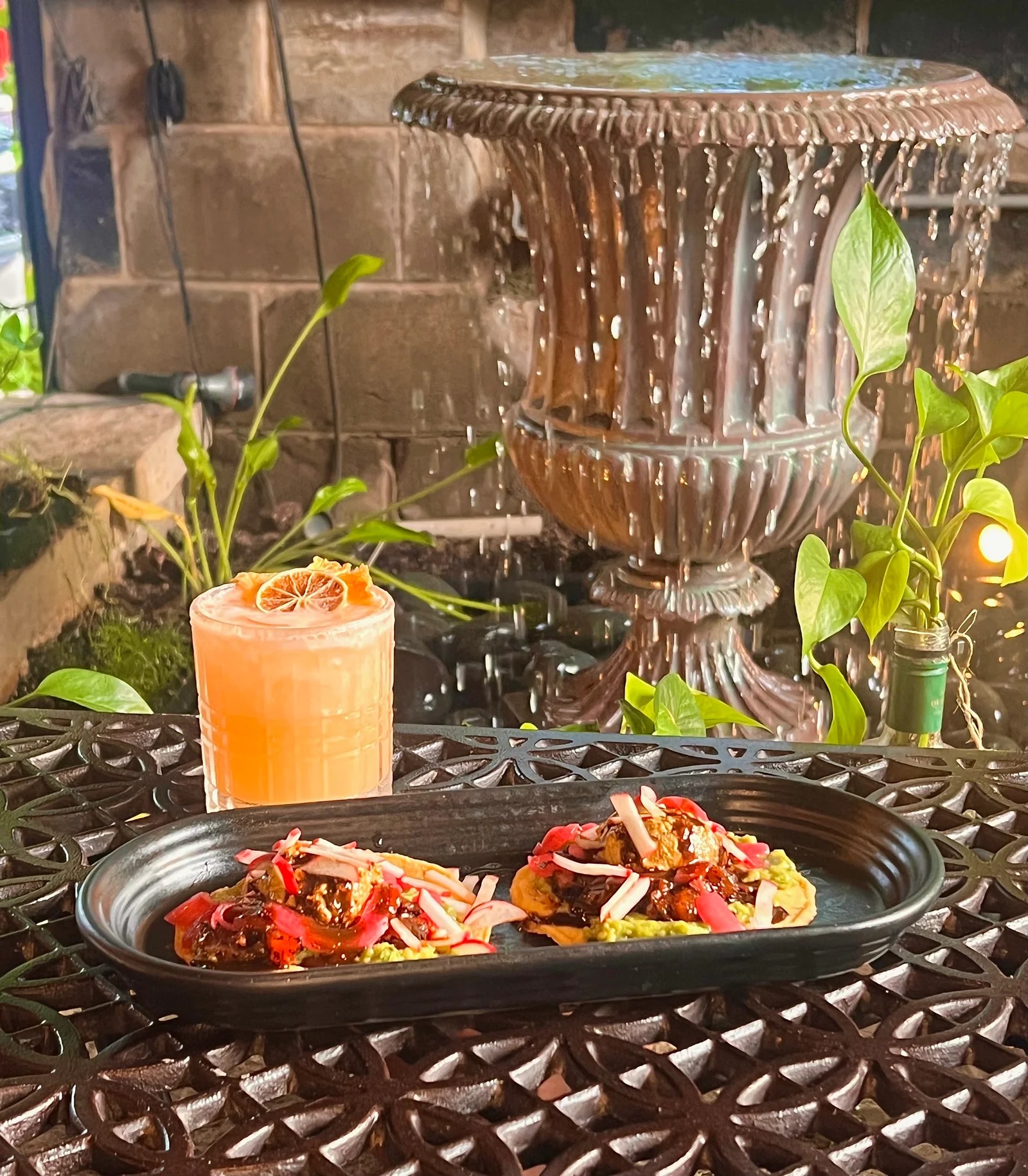 Tostaditas de Ahi Tuna with an orange cocktail beside the patio fountain.