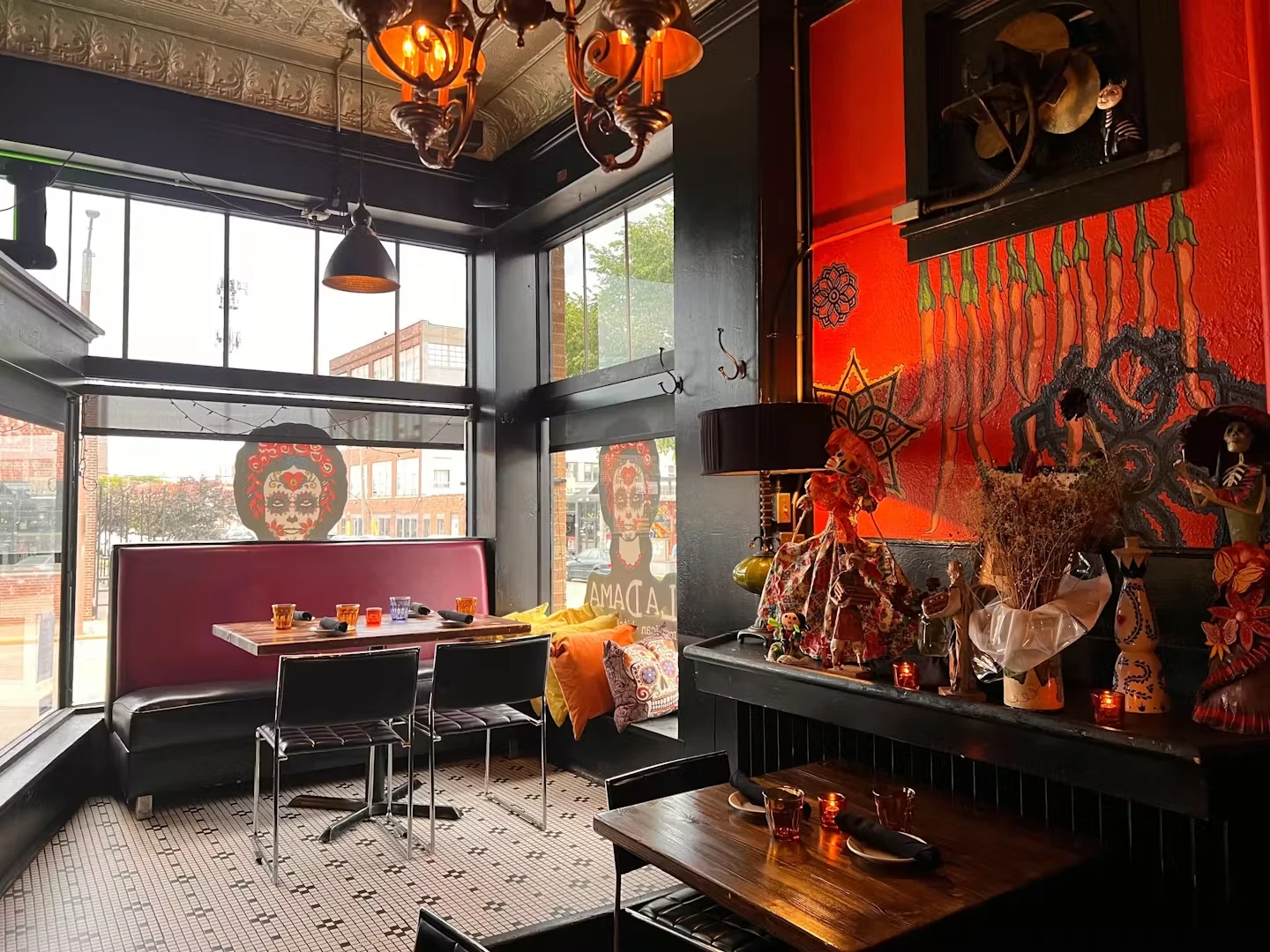 La Dama’s dining room with bright red murals, dark wood, and a tin ceiling